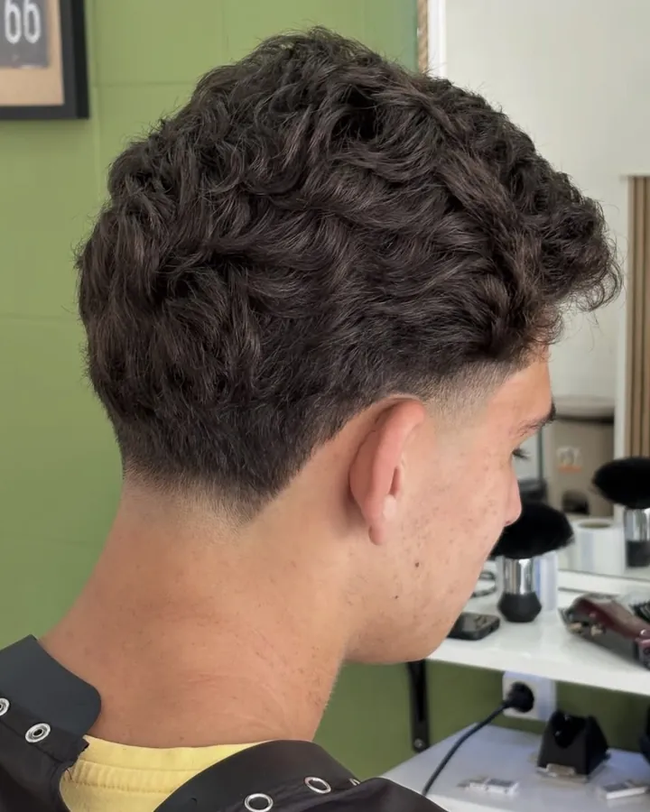 Cabelo com caracóis no topo e fade na nuca, visto de trás