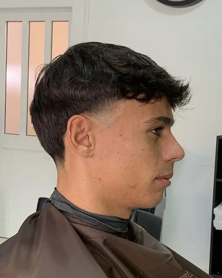 Perfil com franja texturizada e fade junto à têmpora