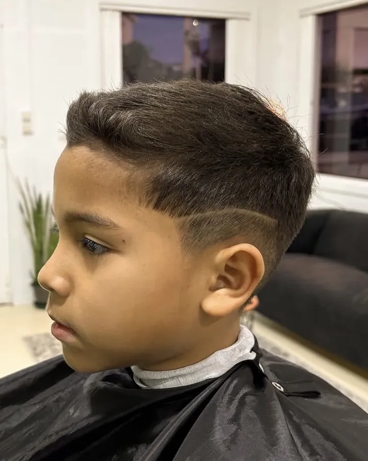 Corte infantil com fade e um risco desenhado na lateral