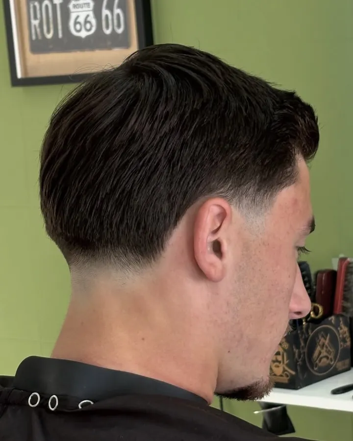 Cabelo penteado para trás com low fade na nuca